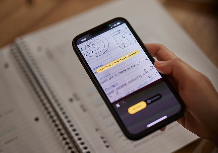 Student scanning notebook with phone